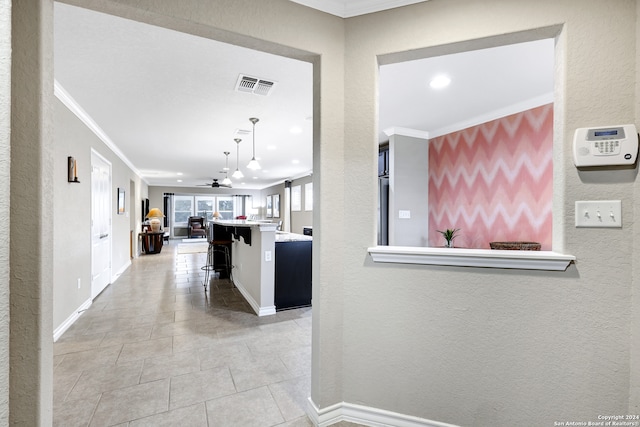 hall with crown molding and light tile patterned floors