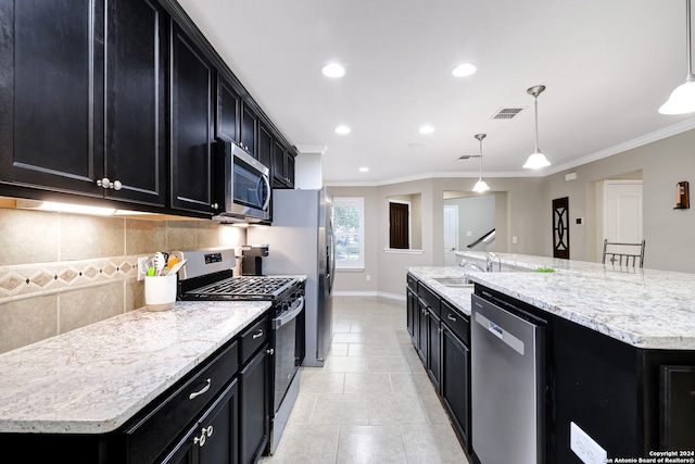 kitchen featuring a large island with sink, appliances with stainless steel finishes, hanging light fixtures, and backsplash