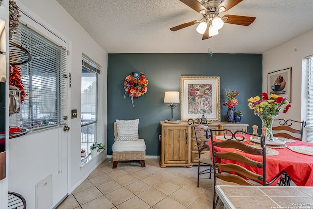 dining space with ceiling fan, a textured ceiling, and light tile patterned flooring