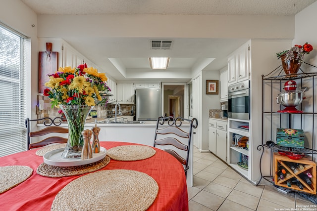 tiled dining area with sink and a raised ceiling