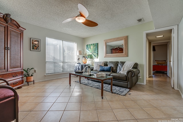 living room featuring ceiling fan, a textured ceiling, and light tile patterned floors