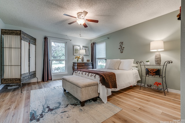 bedroom featuring light hardwood / wood-style floors, a textured ceiling, and ceiling fan