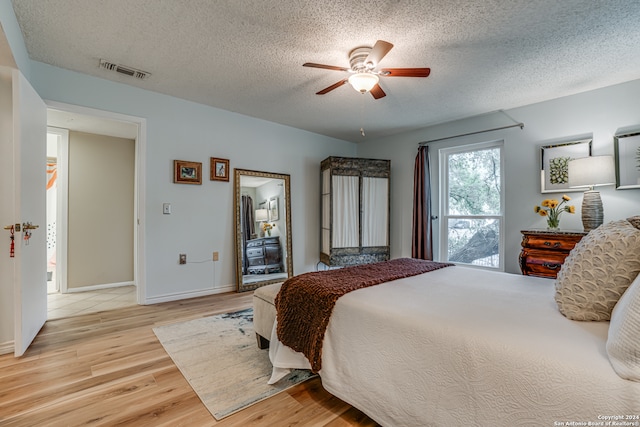 bedroom featuring light hardwood / wood-style floors, a textured ceiling, and ceiling fan