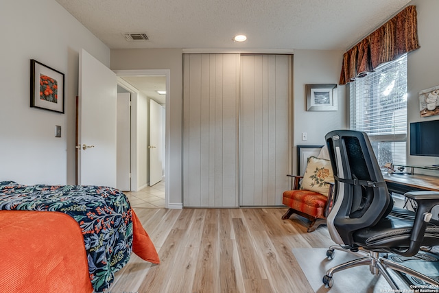 bedroom with a textured ceiling and light hardwood / wood-style flooring