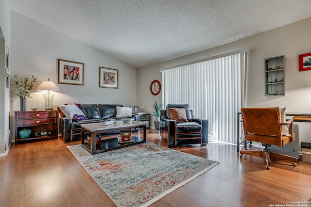 living room with hardwood / wood-style floors, vaulted ceiling, and a textured ceiling