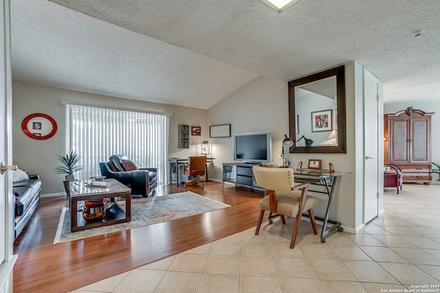 living room featuring vaulted ceiling, a textured ceiling, and light hardwood / wood-style flooring