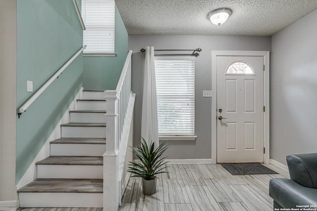 foyer with light hardwood / wood-style floors and a textured ceiling