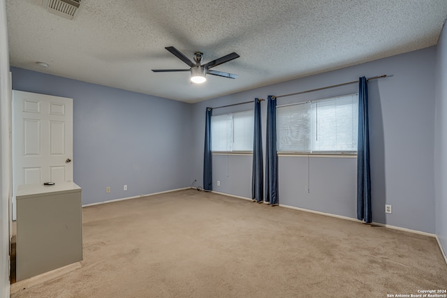 carpeted spare room featuring ceiling fan and a textured ceiling