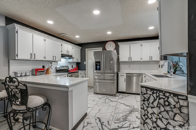 kitchen with white cabinetry, appliances with stainless steel finishes, sink, and kitchen peninsula