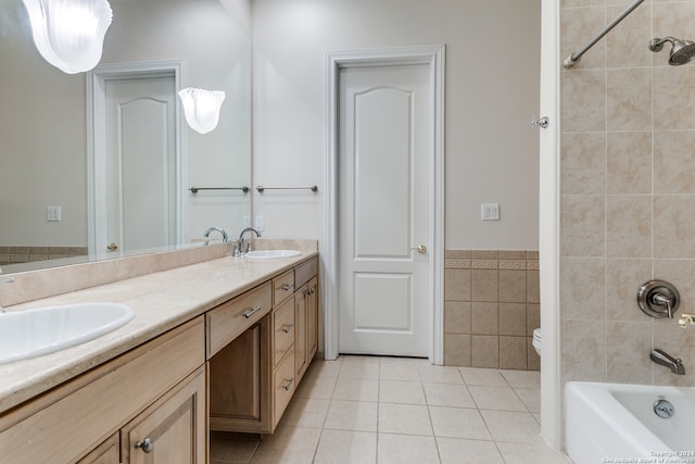 full bathroom with tile walls, tiled shower / bath combo, vanity, tile patterned floors, and toilet