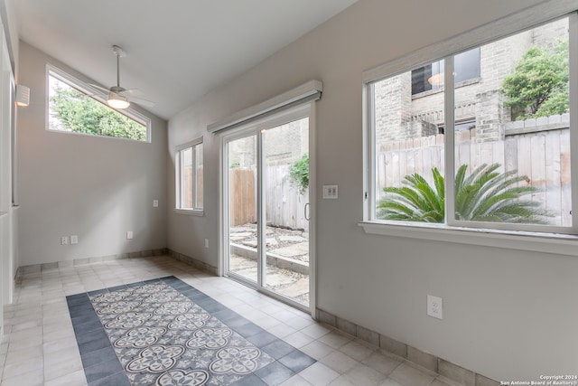 doorway to outside with lofted ceiling, light tile patterned floors, and ceiling fan