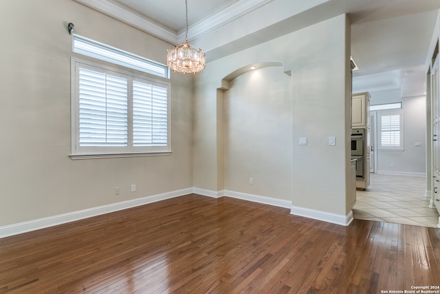 spare room with a notable chandelier, light hardwood / wood-style flooring, and ornamental molding