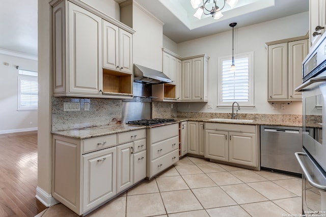 kitchen with wall chimney exhaust hood, sink, decorative light fixtures, appliances with stainless steel finishes, and light stone countertops