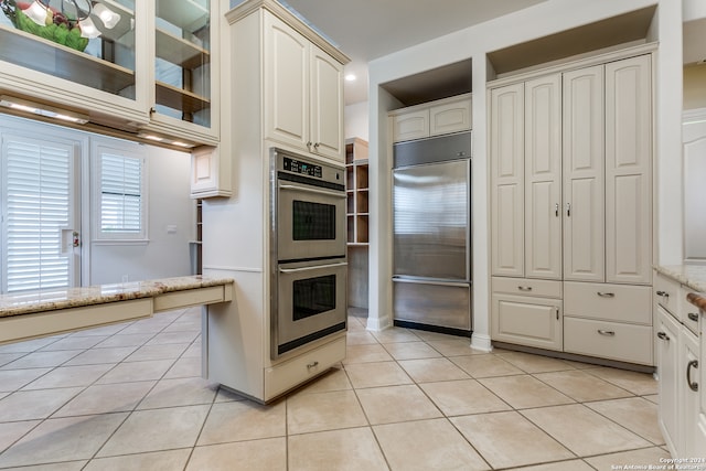 kitchen featuring white cabinetry, light tile patterned floors, light stone countertops, and appliances with stainless steel finishes