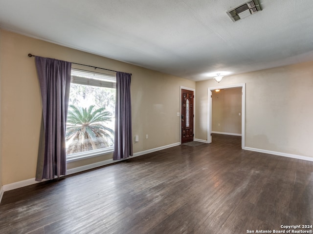 unfurnished room featuring dark hardwood / wood-style flooring and a textured ceiling