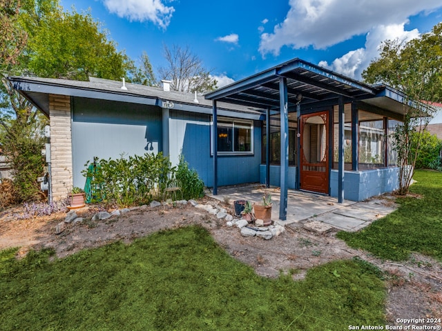 rear view of house featuring a patio area, a sunroom, and a yard