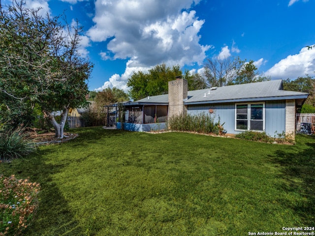 rear view of property with a sunroom and a lawn