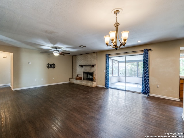 unfurnished living room featuring a textured ceiling, ceiling fan with notable chandelier, dark hardwood / wood-style floors, and a brick fireplace