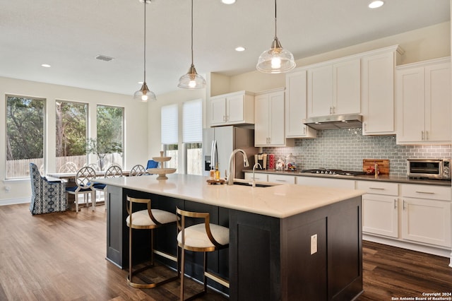 kitchen with dark wood-type flooring, stainless steel appliances, sink, pendant lighting, and white cabinets