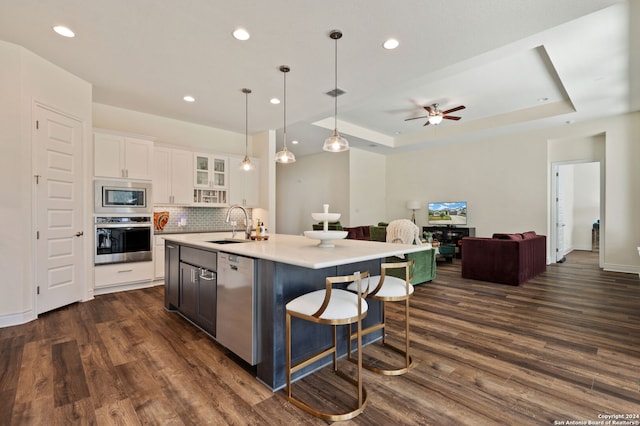 kitchen featuring white cabinets, a center island with sink, dark hardwood / wood-style flooring, decorative light fixtures, and stainless steel appliances