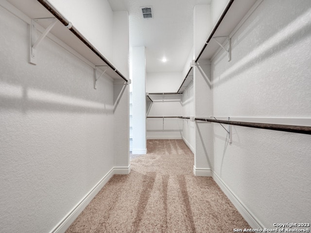 walk in closet featuring light colored carpet