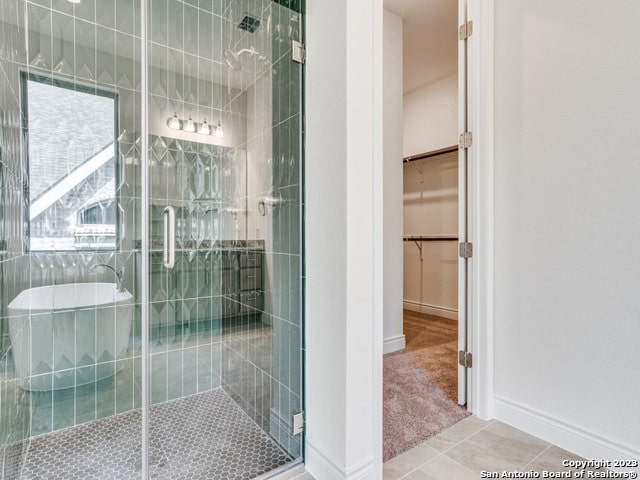 bathroom with a shower with door and tile patterned flooring