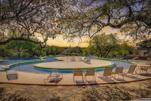 pool at dusk with a patio area