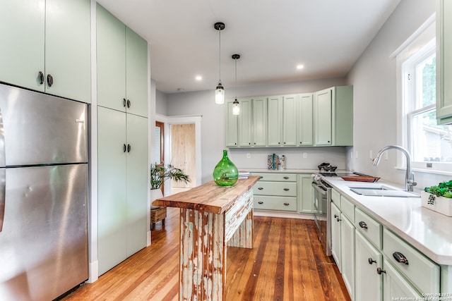 kitchen with sink, stainless steel fridge, green cabinets, and light hardwood / wood-style floors