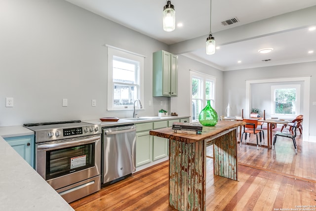 kitchen featuring ornamental molding, stainless steel appliances, sink, light hardwood / wood-style floors, and decorative light fixtures