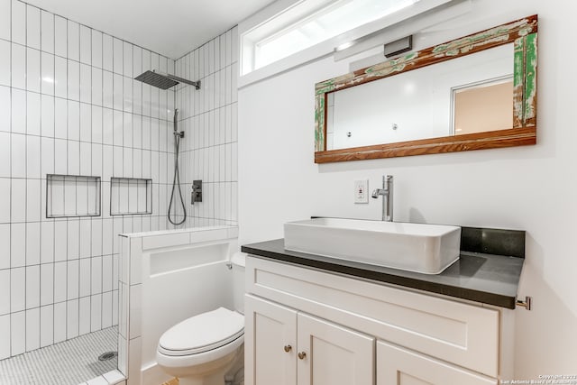 bathroom with vanity, toilet, and a tile shower