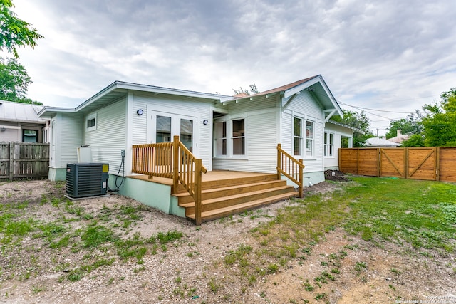 back of property featuring cooling unit, a deck, and a lawn