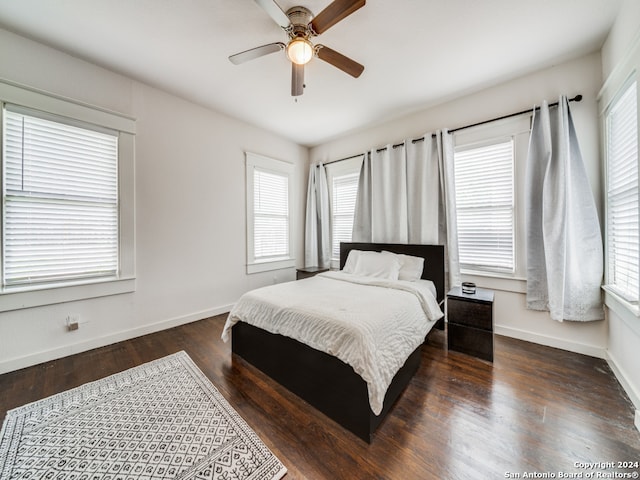 bedroom with multiple windows, ceiling fan, and dark hardwood / wood-style flooring