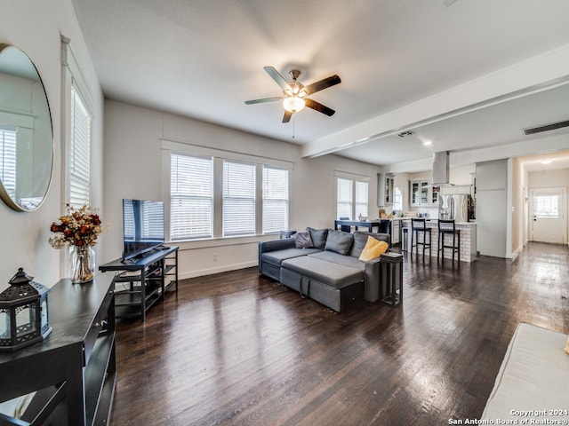 living room with ceiling fan, a healthy amount of sunlight, beam ceiling, and dark hardwood / wood-style flooring