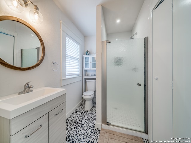 bathroom with a shower with door, vanity, toilet, and tile patterned floors