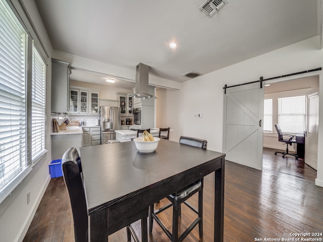 dining space featuring a barn door and dark wood-type flooring