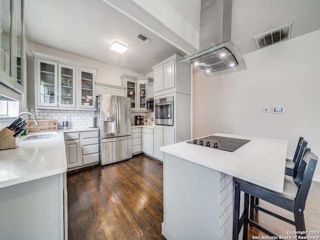 kitchen featuring island exhaust hood, white cabinets, a breakfast bar area, appliances with stainless steel finishes, and dark hardwood / wood-style flooring