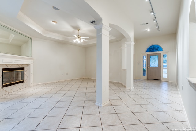 entryway with ceiling fan, light tile patterned flooring, a raised ceiling, and a premium fireplace