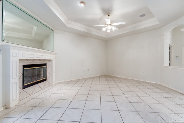 unfurnished living room with a tray ceiling, ceiling fan, crown molding, light tile patterned floors, and a fireplace