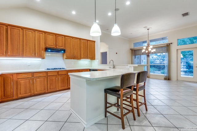 kitchen featuring hanging light fixtures, an inviting chandelier, a kitchen bar, light tile patterned floors, and ornamental molding