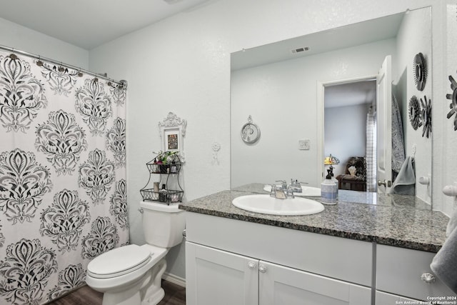 bathroom featuring vanity, hardwood / wood-style floors, walk in shower, and toilet