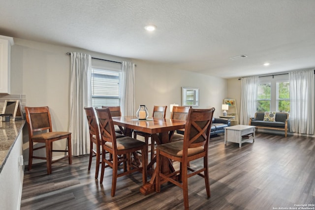 dining space with a textured ceiling and dark wood-type flooring