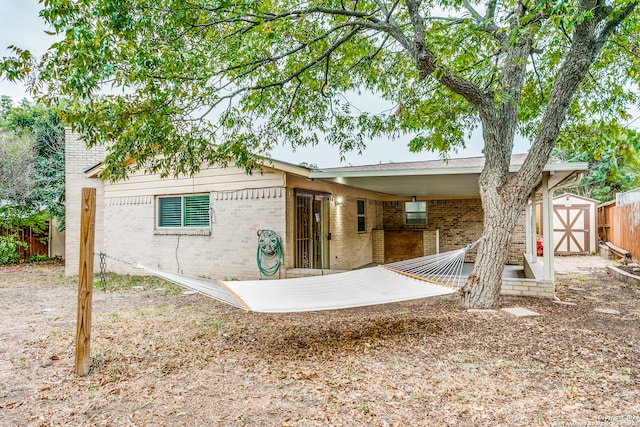 rear view of property featuring a storage unit