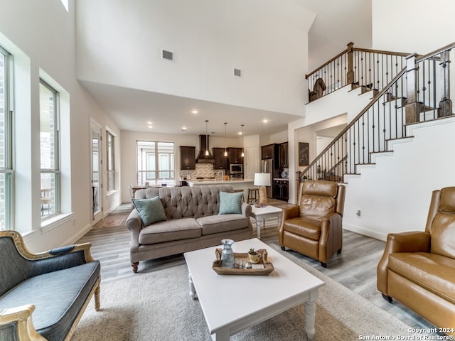 living room with light hardwood / wood-style flooring and a towering ceiling