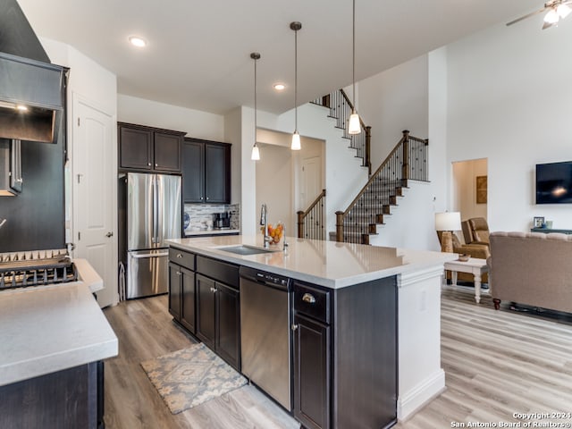 kitchen featuring sink, appliances with stainless steel finishes, decorative light fixtures, and an island with sink