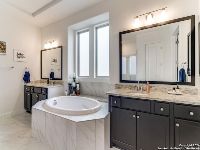 bathroom with healthy amount of natural light, a bath, marble finish flooring, and vanity