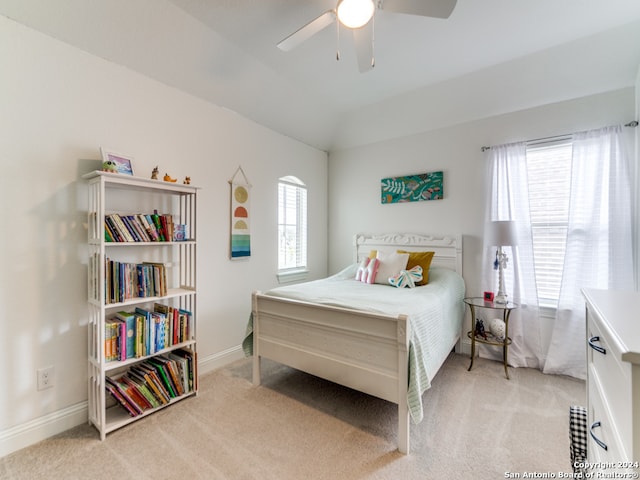 bedroom with ceiling fan, vaulted ceiling, multiple windows, and light colored carpet