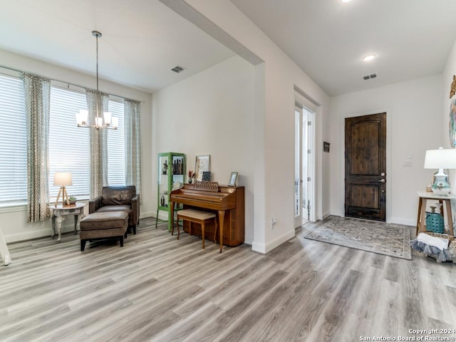 foyer entrance with a chandelier, light wood-type flooring, and baseboards