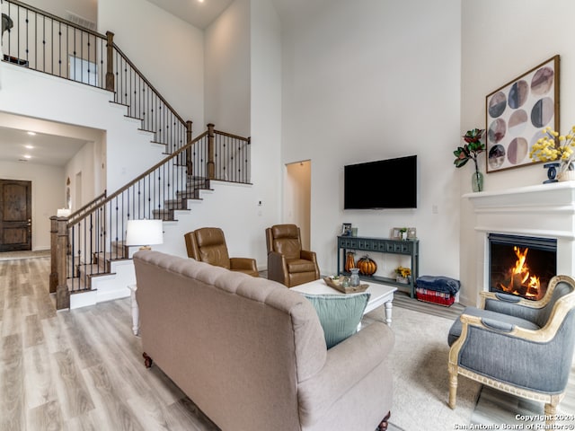 living room featuring a towering ceiling and light hardwood / wood-style flooring