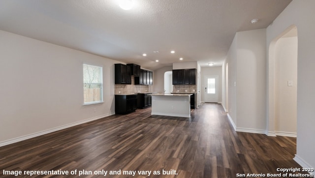 kitchen with a kitchen island, dark hardwood / wood-style floors, a textured ceiling, and tasteful backsplash