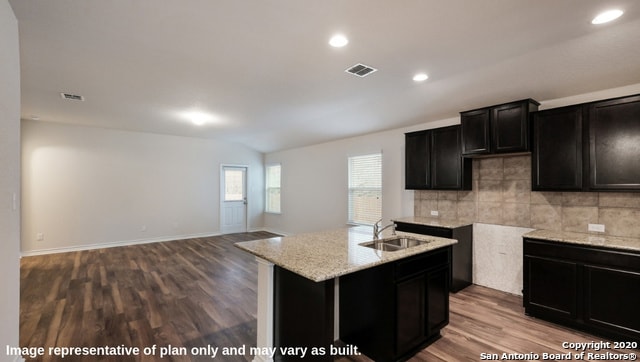 kitchen featuring sink, a kitchen island with sink, decorative backsplash, and wood-type flooring